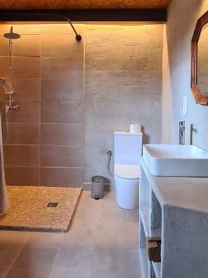 Baño ecológico de Casa Lucía con ducha de obra y detalles en madera natural