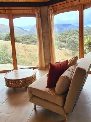 Salón luminoso de Casa Lucía con grandes ventanales y vistas a la naturaleza en Alhama de Granada